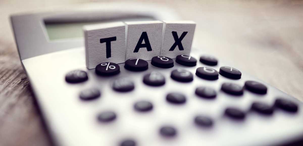 Calculator with the word tax written in wooden block letters